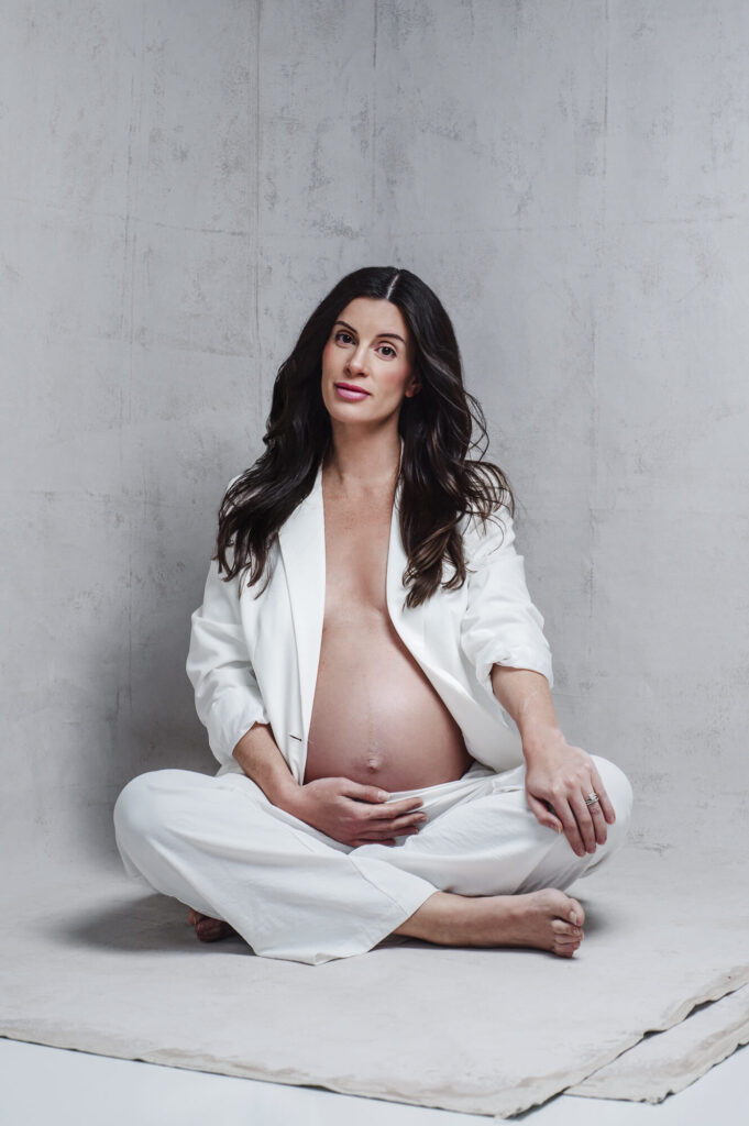 Modern studio portrait of maternity client wearing white suit