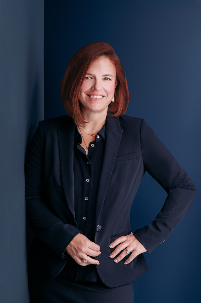 Commercial portrait of red hair women leaning agains blue wall